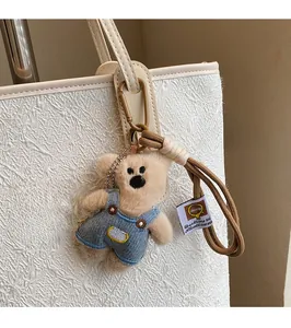 Gros plan d'un charmant ours en peluche en salopette sur un sac à main blanc