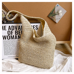 Close-up of beige woven straw tote bag with fabric lining and magnetic metal buckle