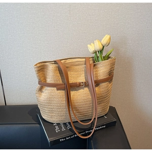 Détail du sac cabas en paille tressée avec lanières en cuir brun et tulipe