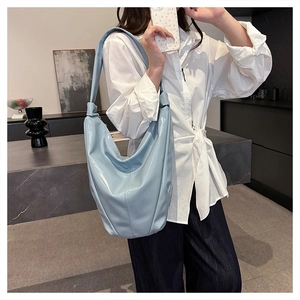 Gros plan d'un sac seau en cuir souple bleu clair avec bandoulière large sur un mannequin