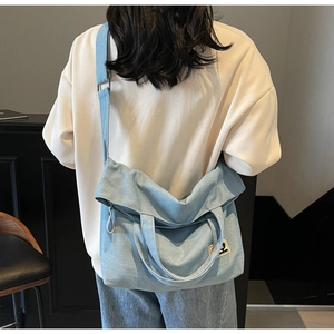 Adjustable strap and handle details on a vintage light blue canvas crossbody tote bag