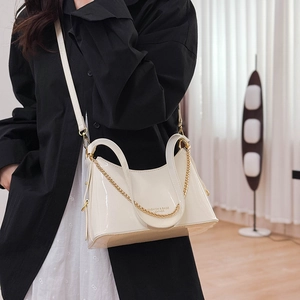 Detail of cream glossy leather bucket bag with metal chain and fashion text engraving