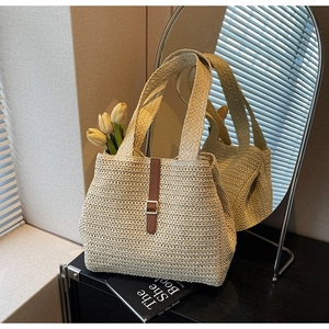 Detail of woven straw tote bag with brown leather clasp and strap in a chic setting