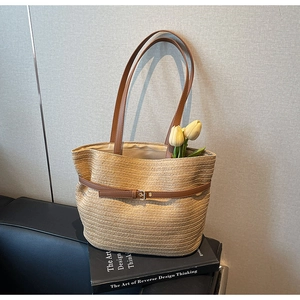 Détail d'un sac cabas en paille tissée avec lanière en cuir brun et boucle élégante