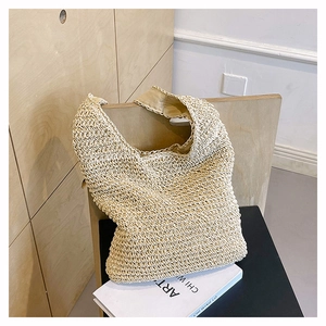 Detail of woven straw tote bag with wavy texture on a wooden chair with books