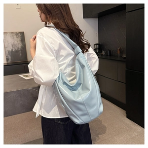 Détail du sac hobo en cuir verni bleu clair avec une bandoulière nouée au design élégant