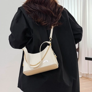Close-up of creamy white patent leather bucket bag with elegant gold chain and hardware