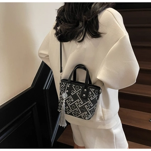 Detail of geometric pattern bucket bag with leather handle and decorative grey tassel