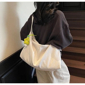 Detail of white nylon tote with pleated texture and yellow flower charm decoration