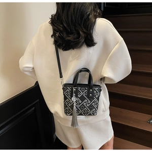 Détail du sac seau avec motifs géométriques et pendentif à pompon gris très élégant