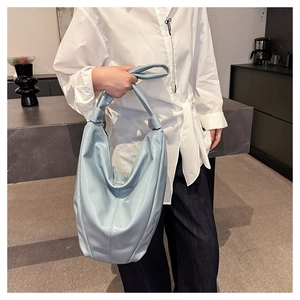 Détail du sac seau en cuir souple bleu clair avec une poignée nouée au design unique