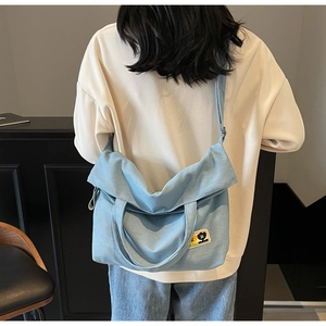 Detail of light blue canvas tote bag with cartoon patch showing back-view fit and size