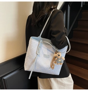 Détail du sac cabas en jacquard bleu clair avec garniture en cuir et breloque ours