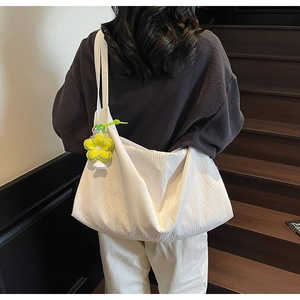Detail of white pleated tote bag with yellow flower charm on model's shoulder