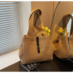 Detail shot of handwoven straw tote bag with black leather strap and silver metal buckle