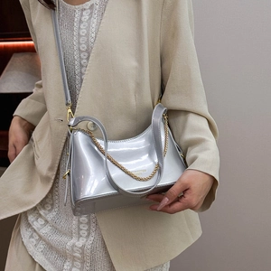 Chic silver mirror crescent handbag with gold chain detail worn on model shoulder
