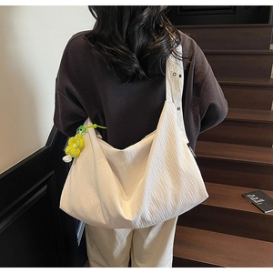 Detailed close-up of white pleated nylon bag featuring a yellow flower pendant and metal button