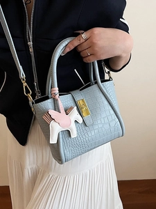Borsa a secchiello celeste con motivo coccodrillo, chiusura oro e ciondolo pegaso