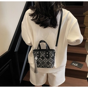 Détail du sac seau en jacquard montrant des motifs géométriques et des poignées en cuir