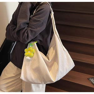 Detail of white pleated hobo bag with textured fabric and yellow flower charm accessory