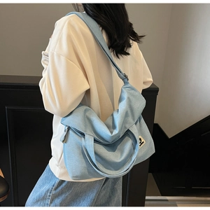 Close-up of a blue denim tote bag featuring a vintage square patch and wide shoulder strap
