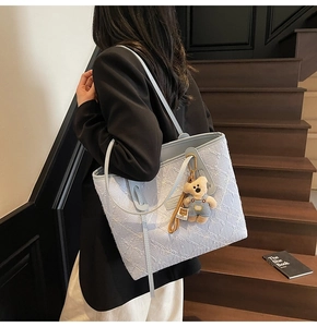 Détail du sac cabas en jacquard bleu clair avec motifs tissés et breloque ours