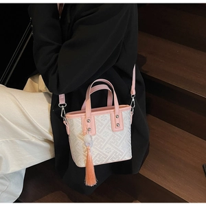 Détail d'un sac seau blanc à motifs avec garniture en cuir rose et pompon élégant