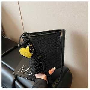 Détail de la texture tressée du sac seau noir avec un charmant cœur jaune sur la sangle