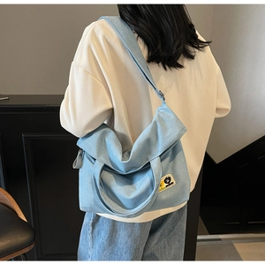 Back view of model wearing a light blue canvas tote bag with decorative cartoon patch
