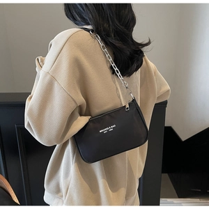 Detail of black nylon baguette bag with silver chain and white logo print lettering