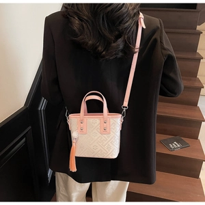 Detail of pink and white bucket bag with geometric patterns and tassel on a crossbody strap