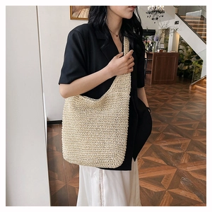 Detail of hand-woven beige straw shoulder bag texture worn by a model in casual setting