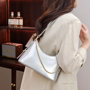 Detail of silver mirror shoulder bag with gold chain strap in upscale home setting