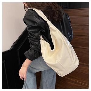 Détail du sac cabas en cuir verni crème avec bandoulière à nœud minimaliste chic