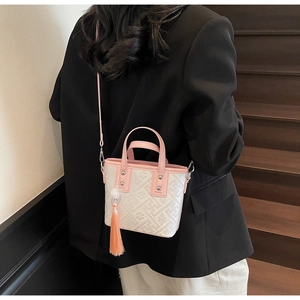Detail of pink embroidered handbag with floral texture, top handles and silk tassel charm