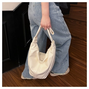 Détail du sac hobo en similicuir crème avec poignée nouée sur des escaliers