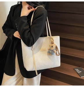 Vue détaillée du sac cabas blanc à texture plissée avec un joli pendentif ours en peluche