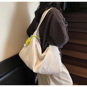 Close-up of white pleated tote bag with yellow sunflower charm on modern indoor stairs