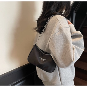Close-up of black nylon shoulder bag with silver chain strap on a model shoulder