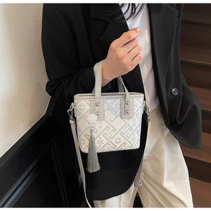 Détail du sac seau en jacquard gris avec motifs géométriques et pompons en soie