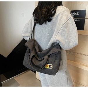 Detailed view of dark grey canvas tote bag with cartoon character patch and wide strap
