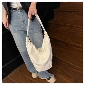 Détail du sac hobo en cuir souple crème avec bandoulière à nœud élégante
