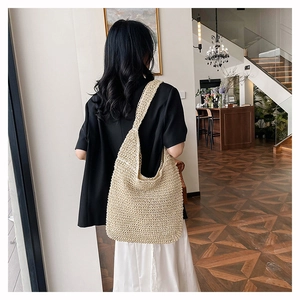 Detailed close-up of beige straw hobo bag with intricate woven texture and thick shoulder strap