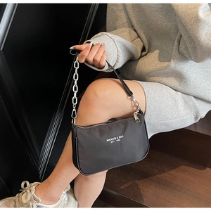 Detail of black nylon shoulder bag with silver chain and white brand logo lettering