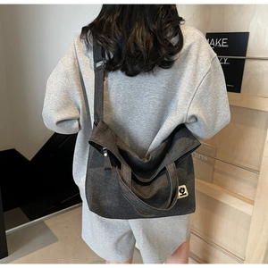 Detail of dark grey washed canvas tote bag featuring a cute bear patch and dual straps