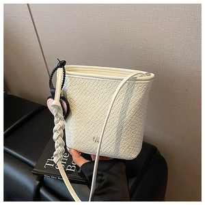 Détail du sac seau blanc avec texture gaufrée crocodile et accent de sangle tissée