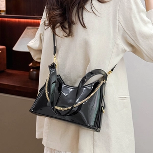 Detail of high-gloss black patent leather bucket bag with gold chain and FASHION logo