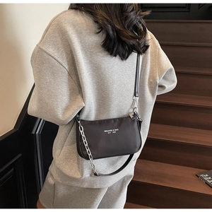 Detailed view of black nylon shoulder bag with silver chain and white logo on back