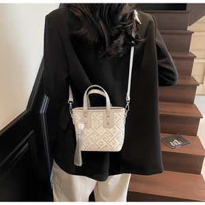 Détail d'un sac cabas beige avec imprimés géométriques vintage et pendentif à pompon