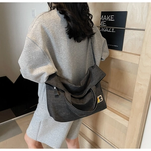 Detail view of dark grey canvas crossbody bag showing cartoon patch and washed fabric texture
